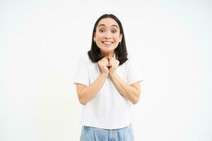 sonriente asiático mujer mirando esperanzado, viendo alguna cosa con excitación, blanco antecedentes foto