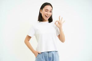 Portrait of confident woman, showing okay, ok sign in approval, nod and say yes, recommend smth, standing over white background photo