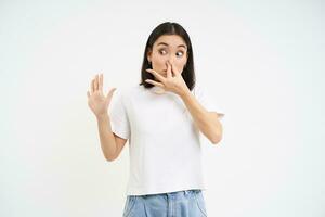 Woman shuts her nose, rejects something stinky, disgusted by bad smell, refuses smelly offer, stands over white background photo