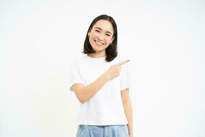 hermosa joven sonriente mujer, señalando bien, demostración bandera, anuncio en blanco vacío Copiar espacio, aislado en blanco antecedentes foto