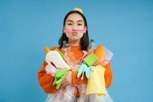 Environment and ecology. Portrait of asian woman holding plastic waste, pile of garbage, blue background photo