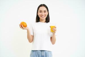 hermosa y sano joven mujer, empieza su día con Fresco jugo, participación naranja Fruta y sonriente, blanco antecedentes foto