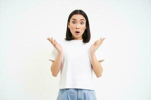 Portrait of woman with surprised face, clap hands, gasps and drops jaw with impressed face, stands over white background photo