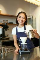 vertical Disparo de linda asiático niña barista, estudiante trabajando en café comercio, torrencial agua en filtrar. fabricación de cerveza, en pie en delantal detrás mostrador en café foto