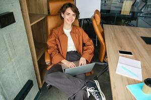 retrato de joven hembra gerente, trabajando mujer en oficina, utilizando computadora portátil, mecanografía en computadora foto