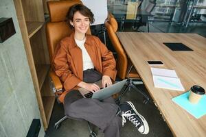 negocio y estilo de vida concepto. joven mujer en casual ropa, trabajando en computadora portátil, sentado en oficina foto