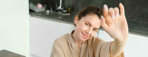 Attractive young cheerful girl baking at the kitchen, making dough, holding recipe book, having ideas photo