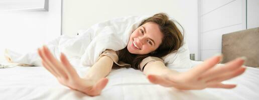 Gorgeous girl laughing and smiling, stretching in hotel bed, enjoying sleepy morning, good nap photo