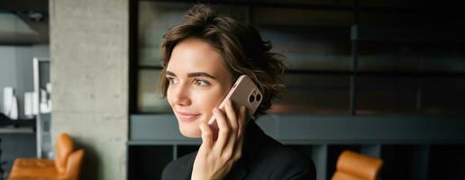 Close up portrait of businesswoman talking on smartphone, having conversation in conference room photo