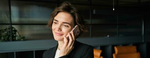 Close up portrait of businesswoman talking on smartphone, having conversation in conference room photo