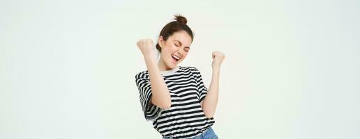 Portrait of happy woman winning, celebrating victory, rooting for team, triumphing, standing over white background photo