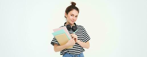 imagen de joven mujer, tutor con libros y cuadernos, vistiendo auriculares terminado su cuello, aislado en blanco antecedentes. estudiante estilo de vida concepto foto