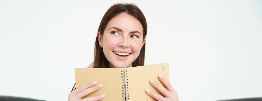 imagen de joven mujer con computadora portátil, participación su personal diario, trabajo planificador, sonriente, leyendo algo, en pie terminado blanco antecedentes foto