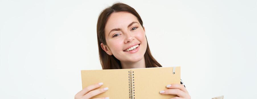 imagen de joven mujer con computadora portátil, participación su personal diario, trabajo planificador, sonriente, leyendo algo, en pie terminado blanco antecedentes foto