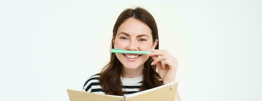 Image of beautiful young woman, student holding notebook, memo planner and pen, smiling and looking happy, isolated against white background photo