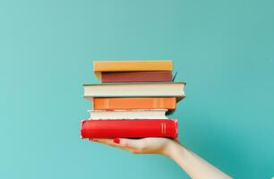 AI generated hand holding stack of books on blue background photo