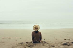 ai generado mujer en sombrero sentado en playa en frente de el mar foto