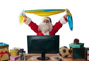 Joyful santa claus, soccer fan, watches a game on television photo