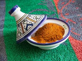 a bowl of spices sits on a colorful table photo