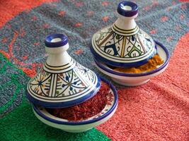 two small bowls with spices on a colorful table cloth photo