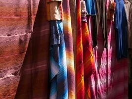 a row of colorful cloths hanging on a rack photo