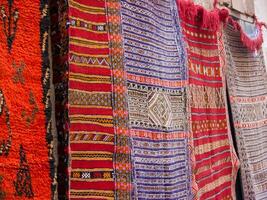 a row of colorful rugs on display in a market photo