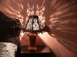 un cama con un lámpara en eso y un sombra en el pared foto