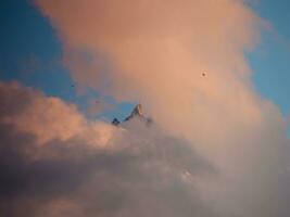 un montaña con nubes y aves volador encima eso foto