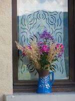 a vase with flowers sitting on a window sill photo