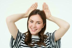 Image of beautiful young woman, posing with animal ears on head and smiling, making cute face, white background photo