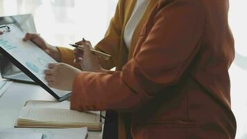 negocio equipo reunión trabajando con nuevo puesta en marcha proyecto, discusión y análisis datos el cartas y gráficos digital tableta, calculadora, ordenador portátil computadora usando, negocio Finanzas y contabilidad concepto. video