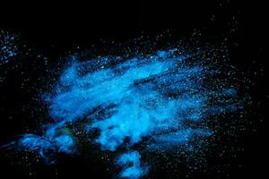 Blue powder explode cloud on black background. Launched blue dust particles splash on  background. photo