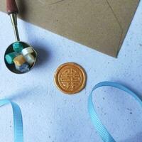 Blank envelope, wax seal stamp and sealing wax bead on blue background photo