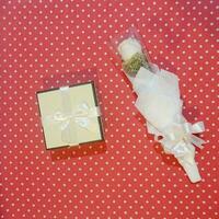 a vertical shot of a white box with a bow and a bouquet of dried flowers on a white background photo