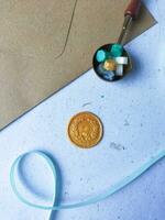 a vertical shot of wax coin with ribbon, wax bead on grey surface photo