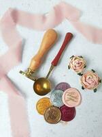 a top view of colorful wax bead and sealing wax with green silk ribbon on an old grey surface photo