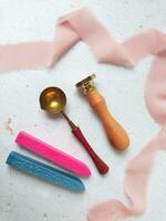 a top view of colorful wax bead and sealing wax with green silk ribbon on an old grey surface photo