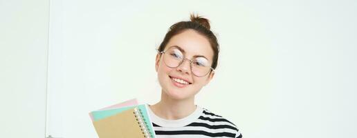 retrato de joven mujer, tutor en anteojos, participación su cuadernos y documentos, sonriente a cámara, en pie terminado blanco antecedentes foto