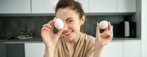 Attractive young cheerful girl baking at the kitchen, making dough, holding recipe book, having ideas photo