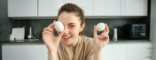 Attractive young cheerful girl baking at the kitchen, making dough, holding recipe book, having ideas photo