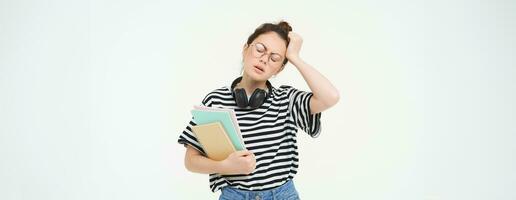 Portrait of young tired student, girl has headache, touching head with troubled face expression, sighing from complicated situation, standing over white background photo