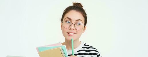 retrato de linda mujer, estudiante en anteojos, pensamiento, en pie pensativo con cuadernos, memorándum notas, blanco antecedentes foto