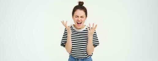 Portrait of angry woman shouting and shaking hands, losing her temper, arguing, standing over white background photo
