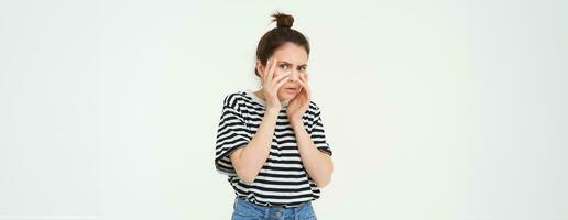 Image of woman looking scared, apalled by something shocking, standing over white background photo