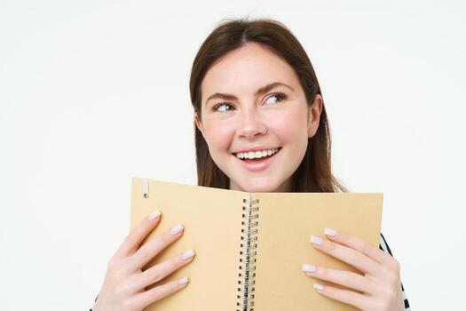 imagen de joven mujer con computadora portátil, participación su personal diario, trabajo planificador, sonriente, leyendo algo, en pie terminado blanco antecedentes foto
