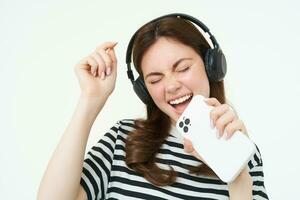 despreocupado mujer canto dentro teléfono inteligente micrófono, jugando móvil karaoke aplicación, teniendo divertido, aislado en blanco antecedentes foto