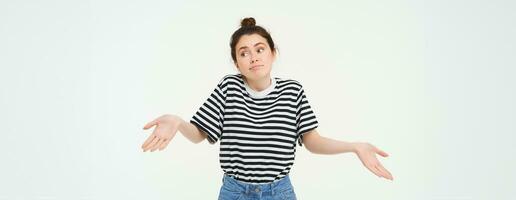 Image of confused brunette girl shrugging shoulders, looks puzzled, isolated over white background photo