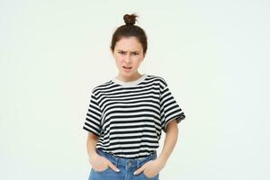 Image of bothered, disappointed young woman, frowning, complaining, looking angry and upset, standing over white background, arguing photo