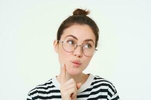 Image of woman in glasses, thinking, pondering smth, looking away with thoughtful face, analizing, standing over white background photo