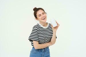 Healthcare and wellbeing. Young woman holding bottle with vitamins, dietary supplements, treatment for good skin and hair, standing over white background photo